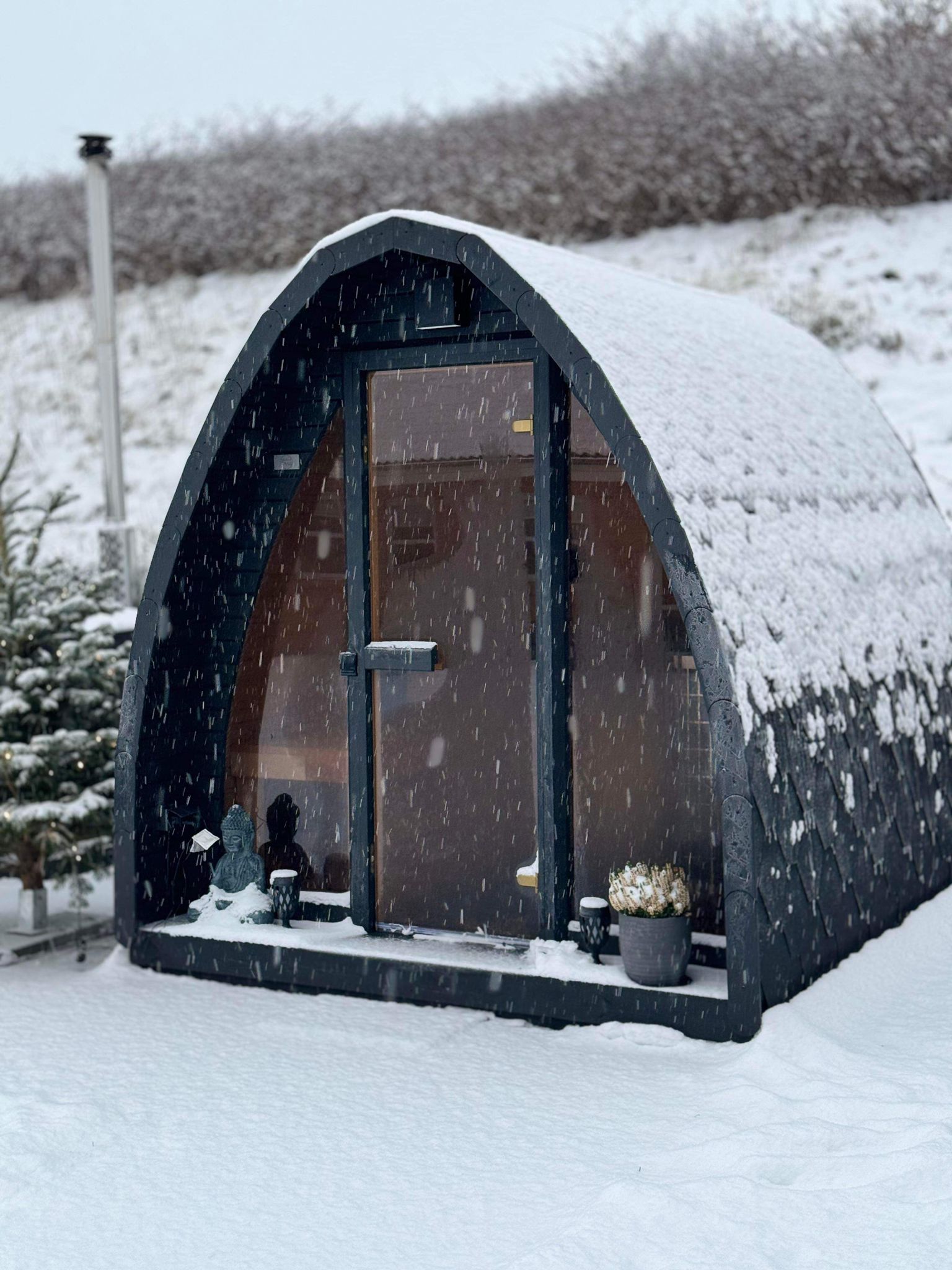 Leaf-shaped solid timber sauna installed in a snowy private garden
